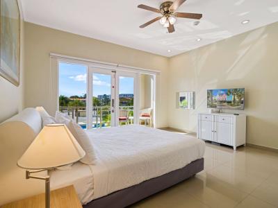 Wake up to stunning tropical views in this spacious bedroom, featuring a plush king bed, private balcony access, and a flat-screen TV for ultimate comfort and relaxation.