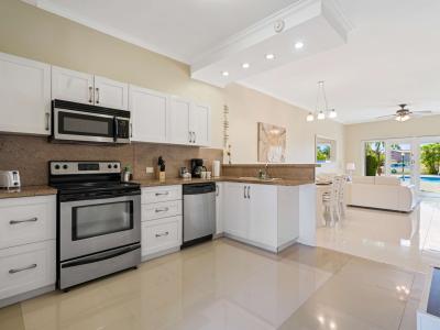 A bright and inviting kitchen with modern appliances, ample storage cabinets, and a front-facing pool view that fills the space with natural light is perfect for a booking retreat!