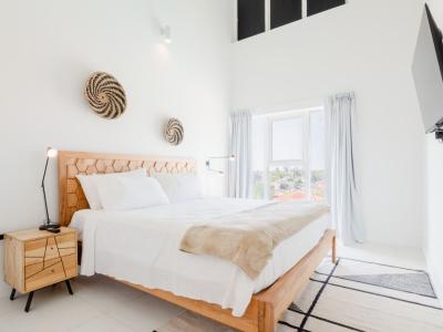 Bedroom 1 features a king size bed and high ceiling with natural light