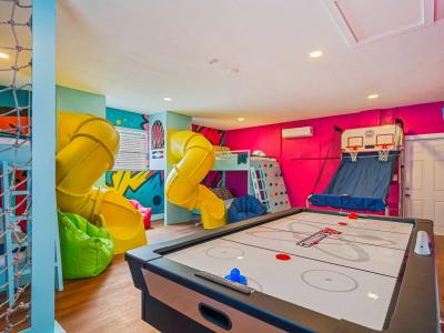 Ultimate kids' paradise featuring two double-over-double bunk beds with a slide, a fun climbing wall, an exciting air hockey table, and a thrilling basketball game