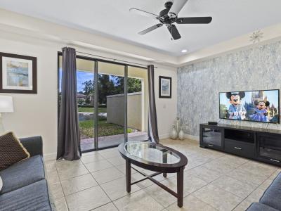 The entry opens to a bright, open-concept living room with a smart TV, a modern sitting area, and views of the lake through sliding doors that lead to the patio.