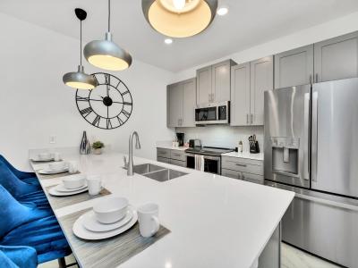 Polished kitchen of the townhouse in Kissimmee Florida - Well-lit workspace with strategically placed task lighting - Integrated appliances for a seamless and stylish appearance - Breakfast bar and high chairs