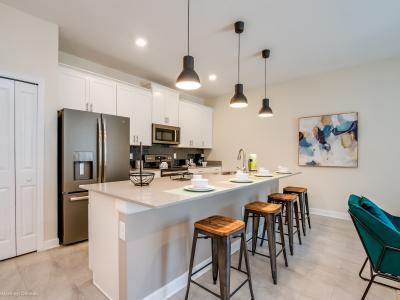 Lush kitchen of the townhouse in Kissimmee Florida - Breakfast bar with high stools - Thoughtful placement of kitchen essentials for easy access - Coordinated kitchen decor for a polished and inviting atmosphere